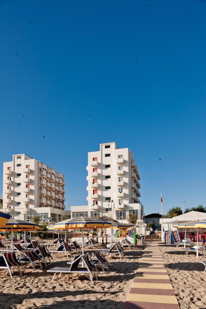 - une rangée de chaises sur une plage avec de grands bâtiments dans l'établissement Hotel Universal, à Senigallia