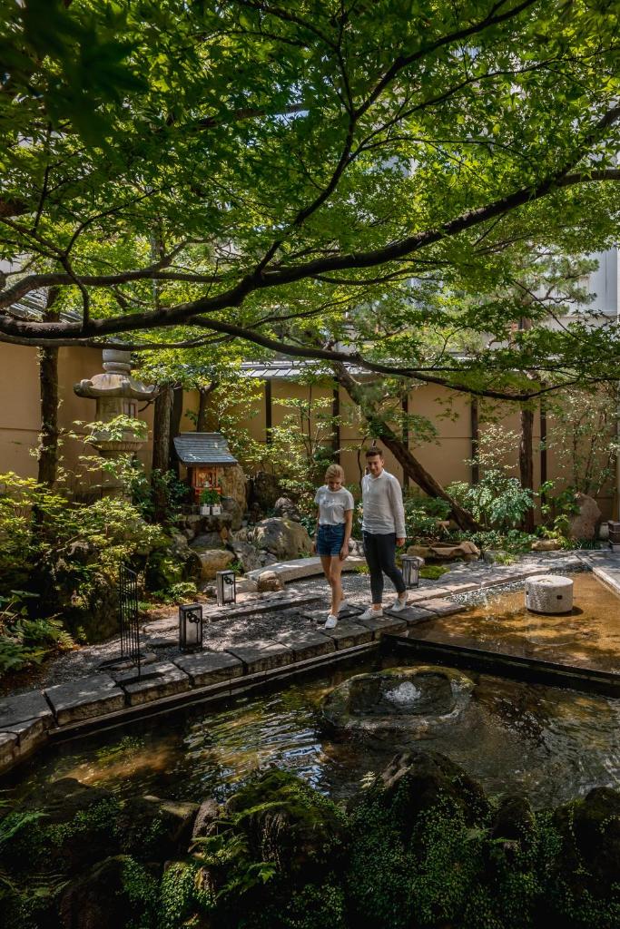 2 personnes marchant autour d'un étang dans un jardin dans l'établissement Nishiyama Ryokan - Established in 1953, à Kyoto
