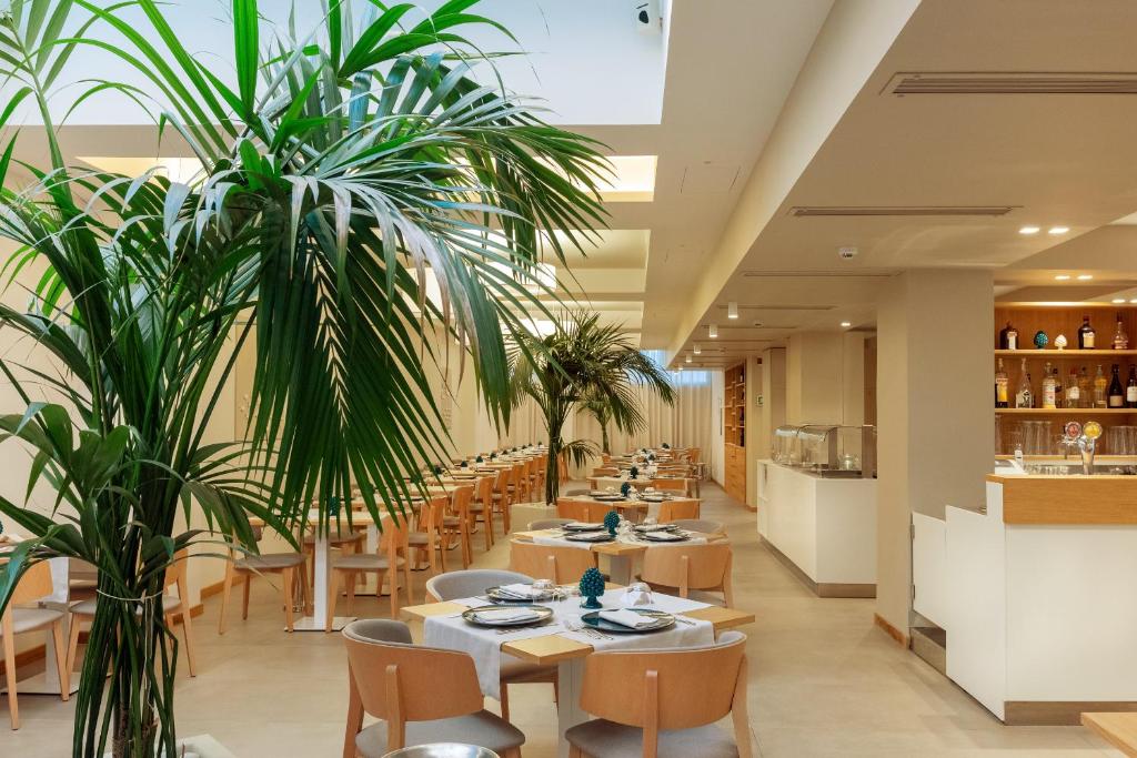 un restaurant avec des tables, des chaises et des plantes dans l'établissement Albatros Beach Hotel, à Letojanni
