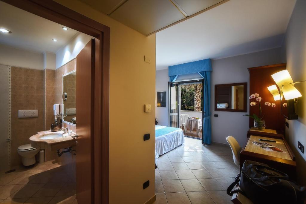 Cette chambre d'hôtel comprend une salle de bains pourvue d'un lavabo et d'un lit. dans l'établissement Hotel Le Palme, à Paestum