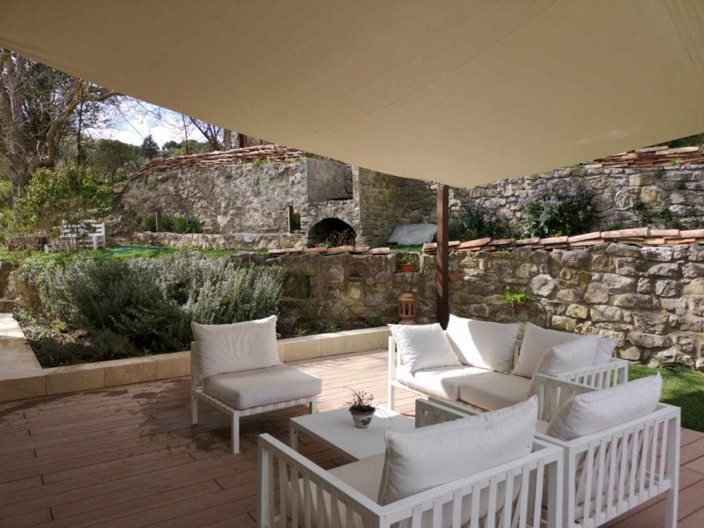une terrasse avec des chaises blanches et un parasol dans l'établissement Molino dei Ciliegi - Splendida villa in Umbria, à San Venanzo