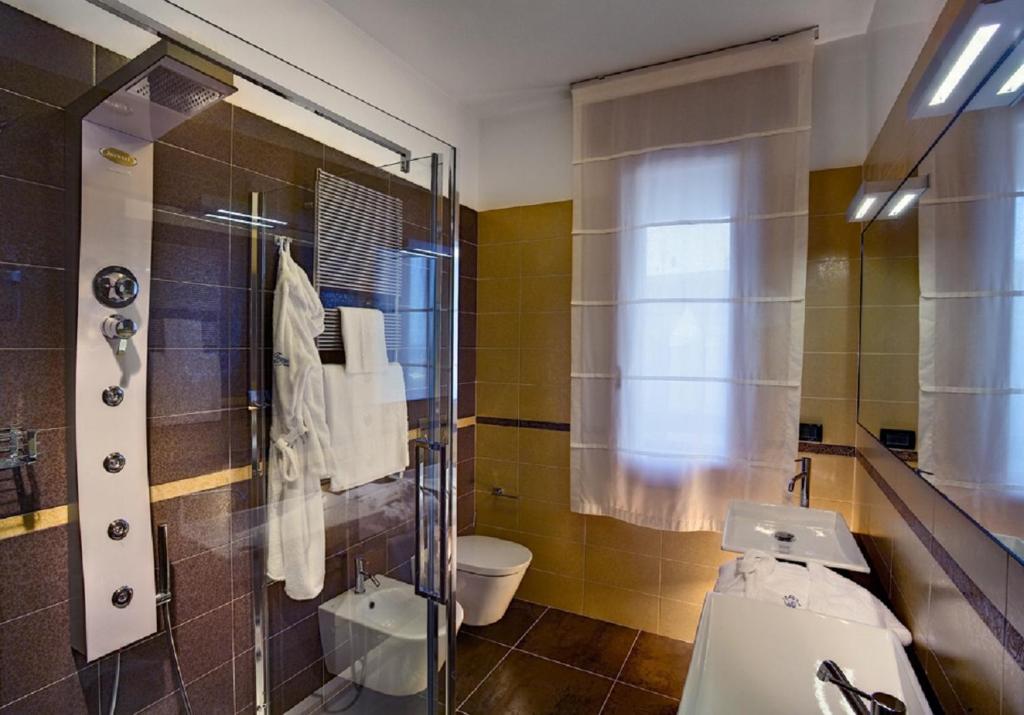 une salle de bain avec toilettes et douche en verre dans l'établissement Hotel Le Tegnue, à Sottomarina