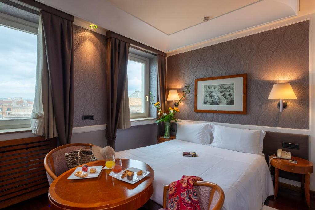 une chambre d'hôtel avec un grand lit et une table dans l'établissement Grand Hotel Ortigia, à Syracuse 78 autres photos