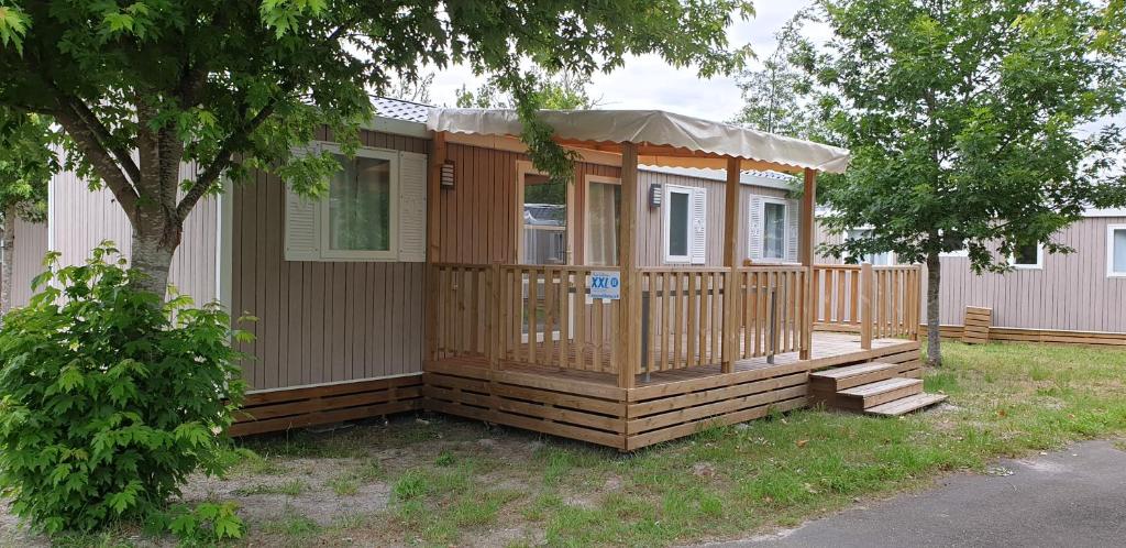 une petite maison avec un porche et une terrasse dans l'établissement Mobil Home XXL 4 chambres - Camping Le Domaine de Beaulieu, à Givrand