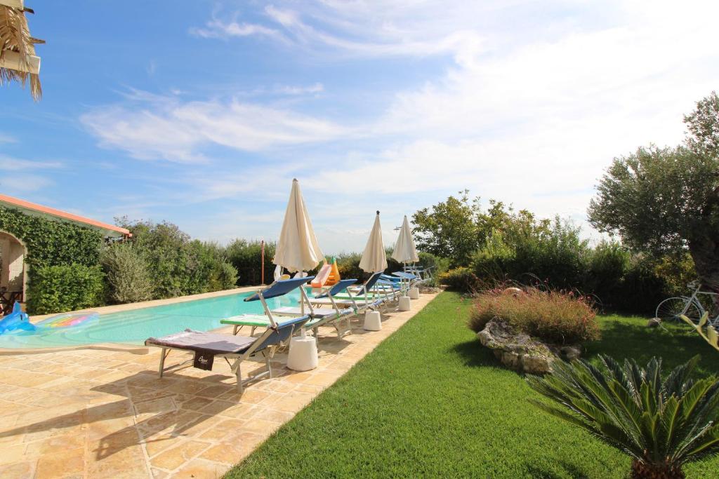 - une rangée de chaises avec des parasols et une piscine dans l'établissement Villa Belvedere, à Ostuni