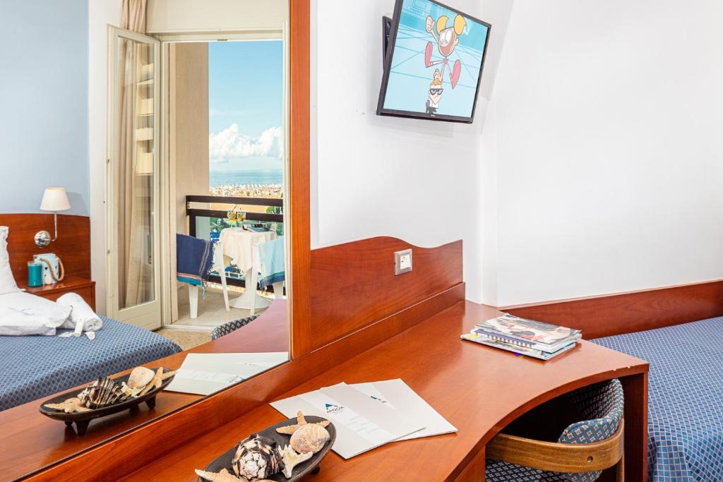une chambre d'hôtel avec un bureau et un miroir dans l'établissement Hotel Palace, à Bibione