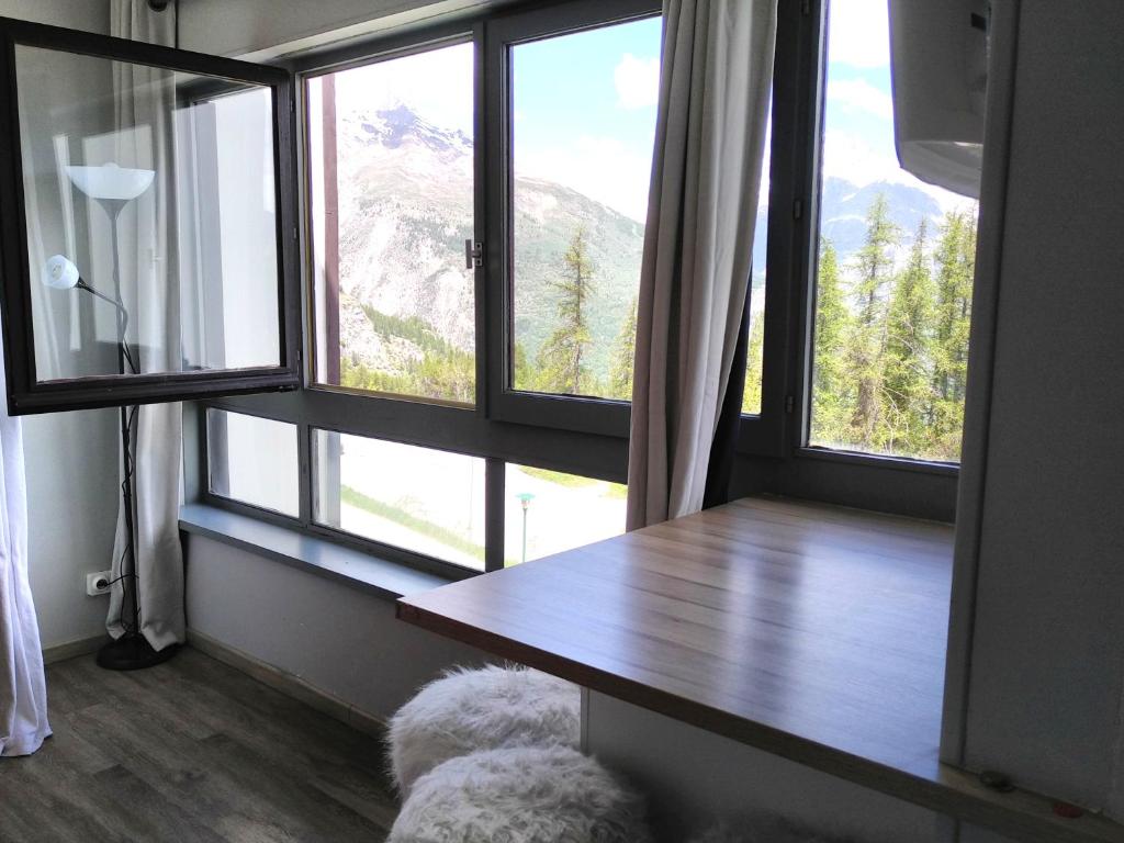Cette chambre dispose d'une grande fenêtre avec une table en bois. dans l'établissement Studio fonctionnel 16m2 avec vue panoramique, à Puy-Saint-Vincent
