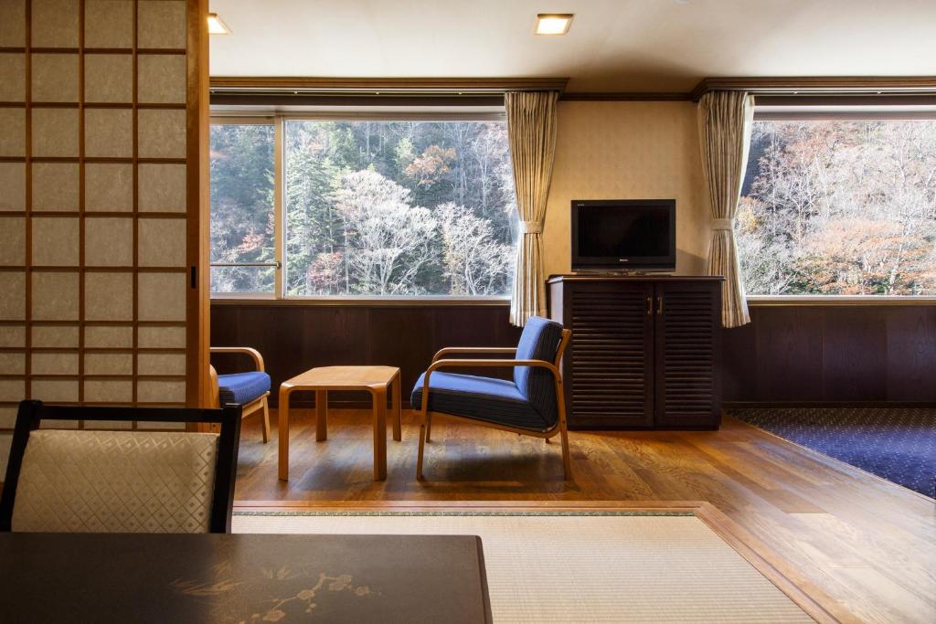 un salon avec une télévision et deux chaises et une table dans l'établissement Choyo Resort Hotel, à Kamikawa