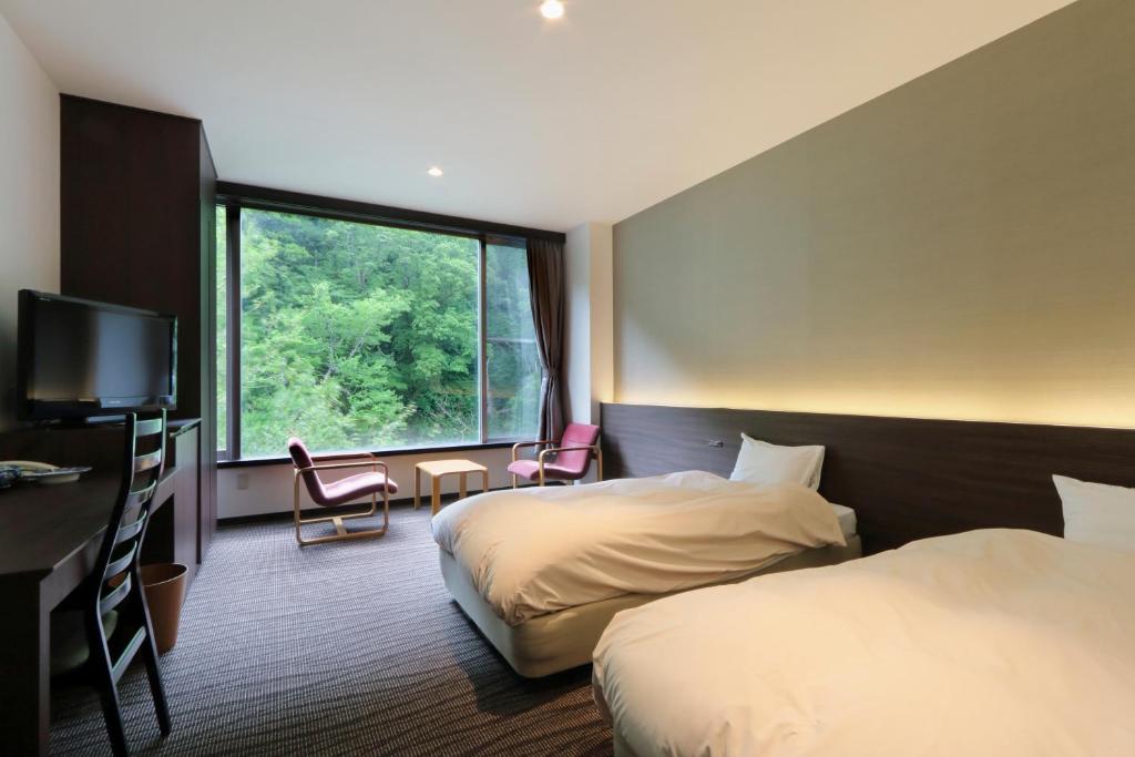 une chambre d'hôtel avec deux lits et une fenêtre dans l'établissement Choyo Resort Hotel, à Kamikawa