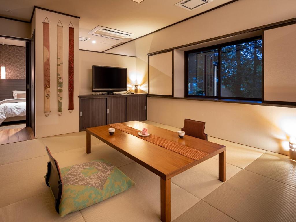 - un salon avec une table en bois et une télévision dans l'établissement Apikogen Mori no Hotel, à Hachimantai