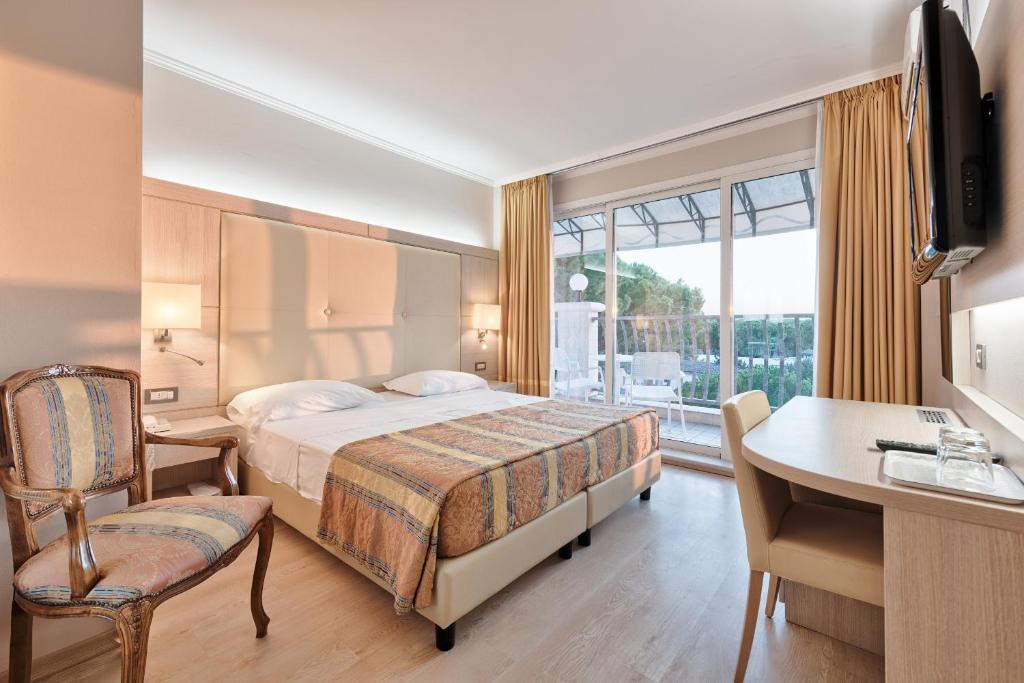 une chambre d'hôtel avec un lit, un bureau et une fenêtre dans l'établissement Hotel Croce Di Malta, à Lignano Sabbiadoro