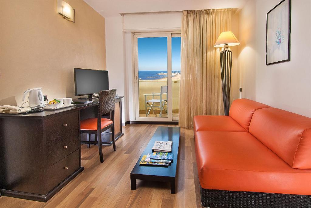 une chambre d'hôtel avec un canapé et un bureau avec un ordinateur dans l'établissement Park Hotel Cattolica & Restaurant, à Cattolica