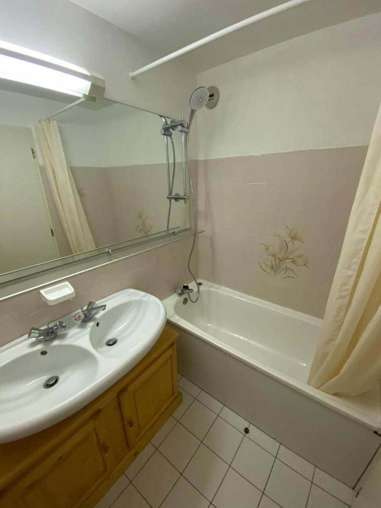 une salle de bain avec un lavabo, une baignoire et un miroir dans l'établissement Parenthèse à la montagne, à Bessans