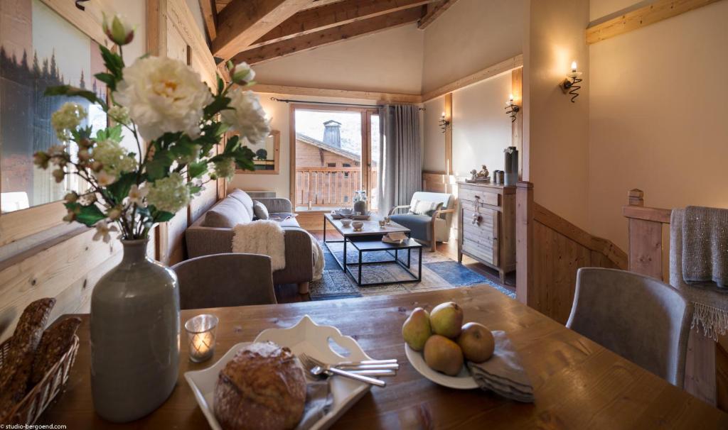un salon avec une table avec un vase de fleurs dans l'établissement Le Hameau de la Sapinière, aux Menuires