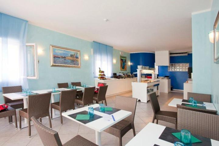 un restaurant avec des tables et des chaises et une cuisine dans l'établissement Hotel Villa Maria, à Caorle