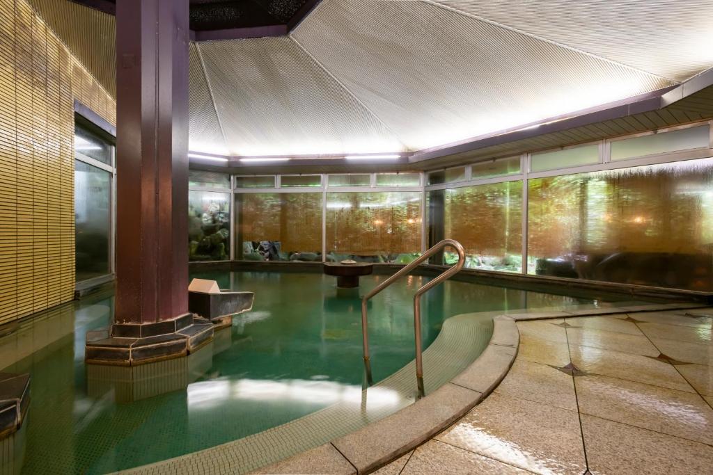 une piscine d'eau verte dans un bâtiment dans l'établissement Senkeien Tsukioka Hotel, à Kaminoyama