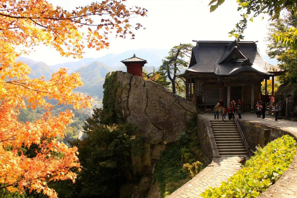 un bâtiment sur le côté d'une falaise à côté d'une montagne dans l'établissement Senkeien Tsukioka Hotel, à Kaminoyama