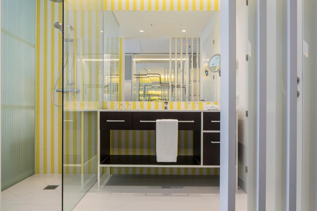 une salle de bain avec un lavabo et une douche avec un miroir dans l'établissement Falkensteiner Hotel & Spa Jesolo, à Lido di Jesolo