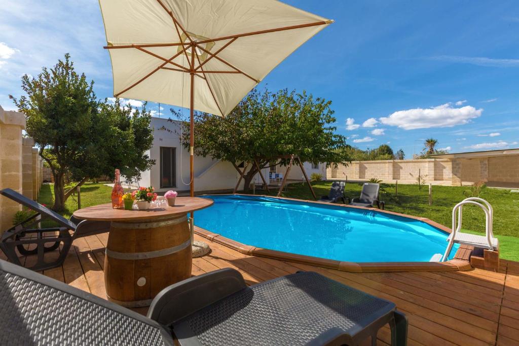 une piscine avec une table et un parasol dans l'établissement Villa Il Fenicottero Salentino by BarbarHouse, à San Pietro in Bevagna