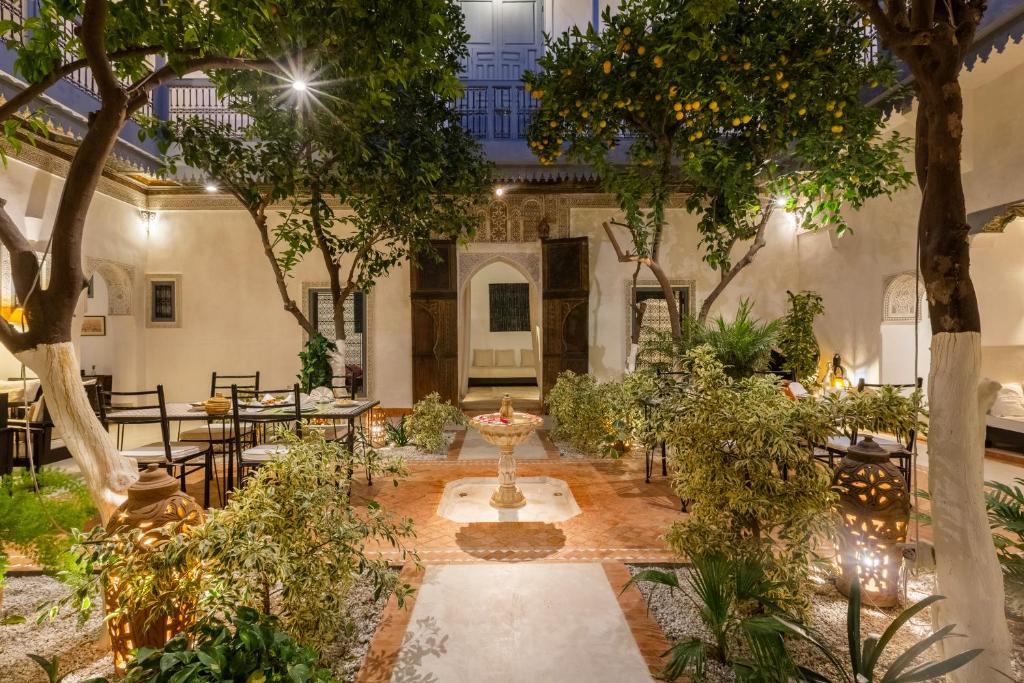 une cour avec des tables, des chaises et des arbres dans l'établissement Riad Tchaikana, à Marrakech