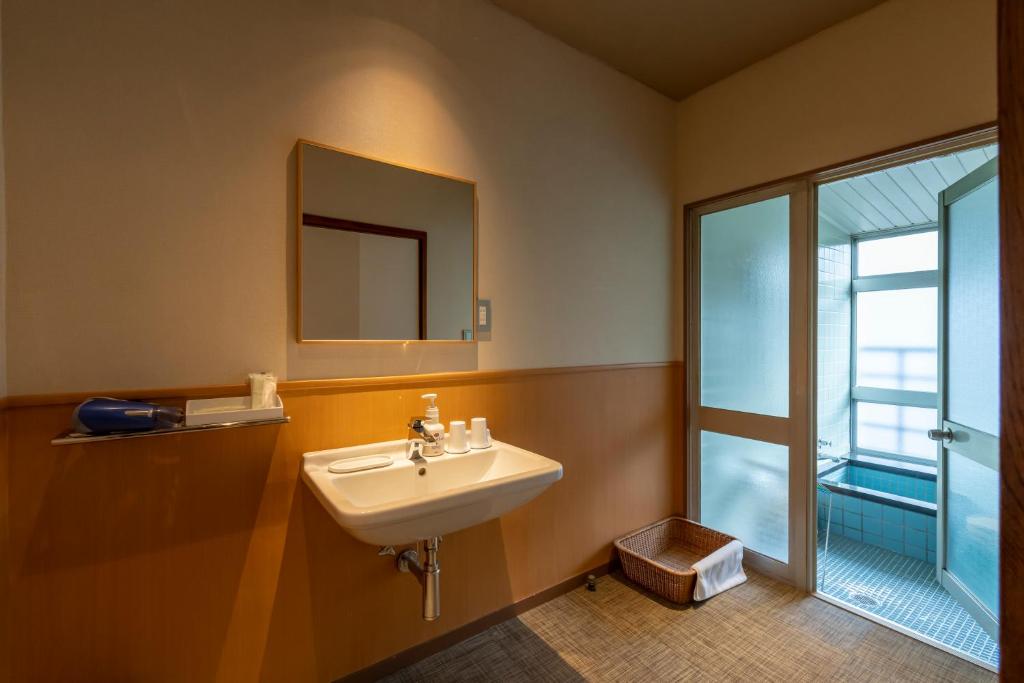 une salle de bain avec un lavabo, un miroir et une fenêtre dans l'établissement Senkeien Tsukioka Hotel, à Kaminoyama