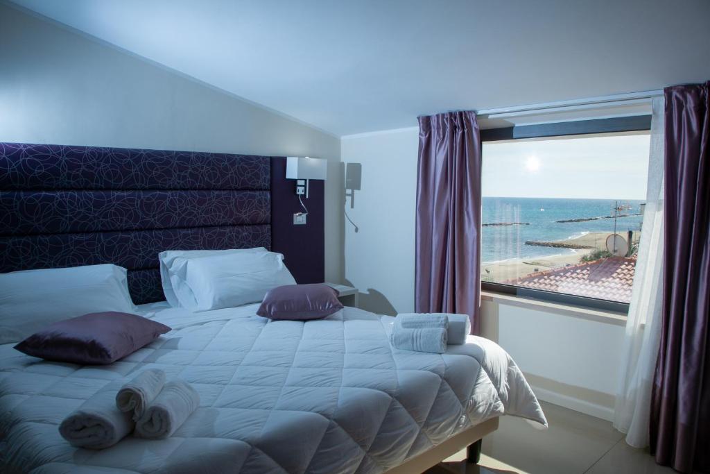 une chambre avec un grand lit avec une grande fenêtre dans l'établissement Hotel Dolce Stella, à Torre Melissa