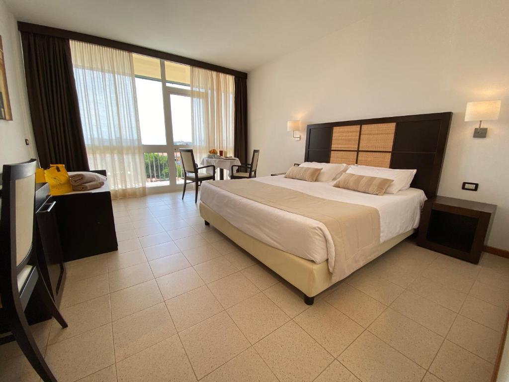 - une grande chambre avec un grand lit et une table dans l'établissement Palace Hotel Regina, à Bibione