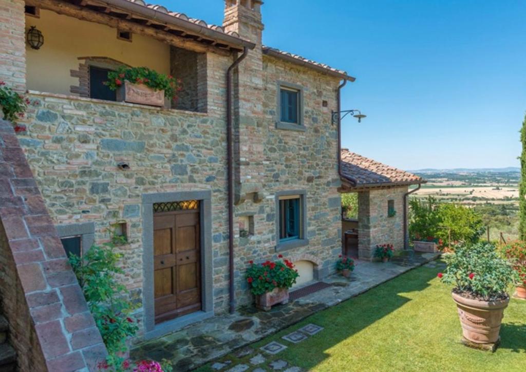 une vue extérieure d'une maison en pierre avec une cour dans l'établissement Casa Lamate, à Cortone