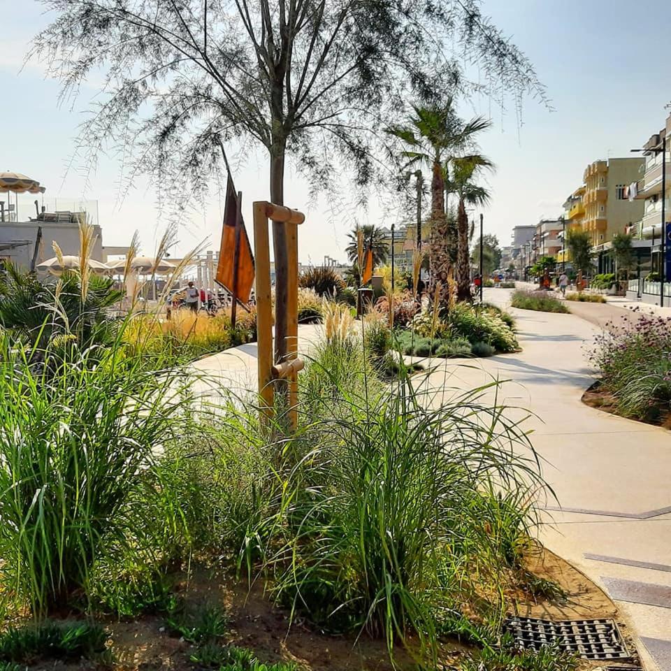 un jardin avec drapeau et plantes sur un trottoir dans l'établissement Hotel Glenn, à Rimini