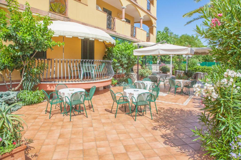 un patio avec tables, chaises et un parasol dans l'établissement Hotel Costazzurra, à Grottammare