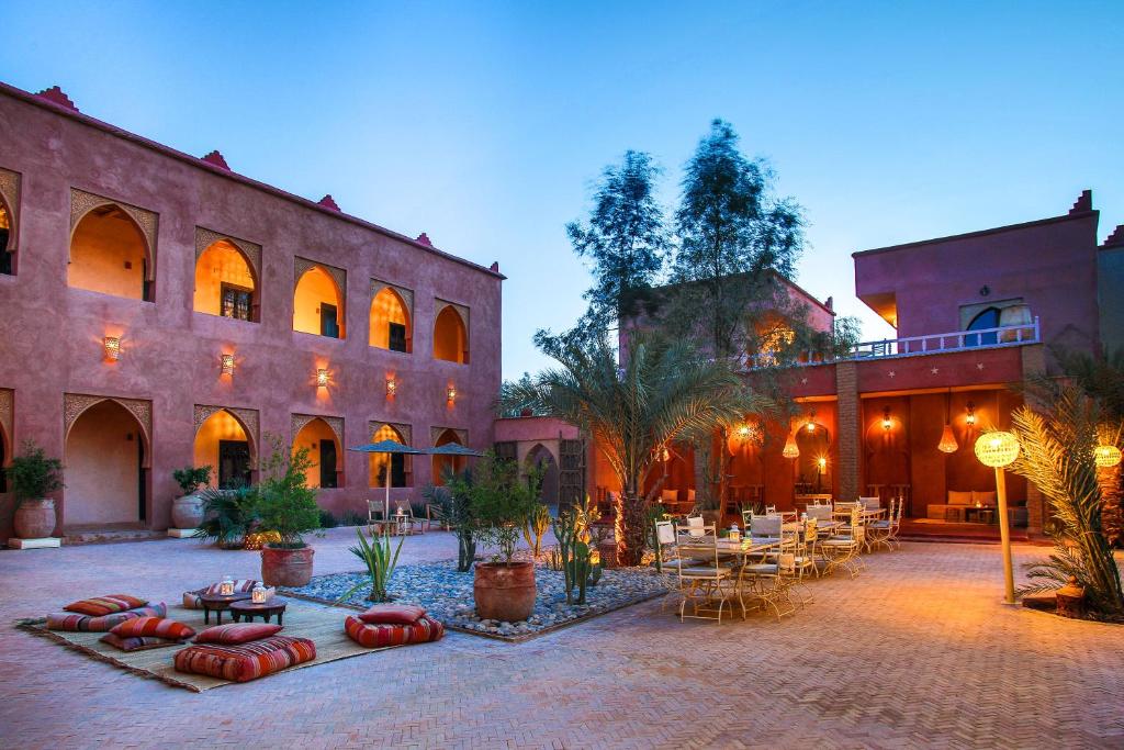 une cour avec des tables et des chaises devant un bâtiment dans l'établissement Riad Madu, à Merzouga