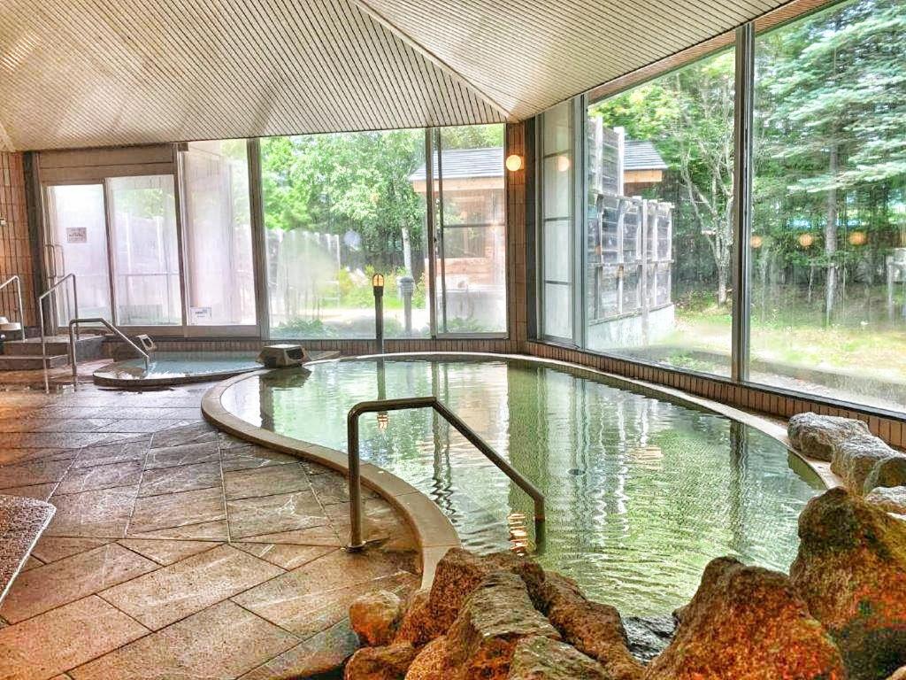 une grande piscine dans un immeuble avec une grande fenêtre dans l'établissement Hotel Tetoraresort Tokachigawa, à Otofuke