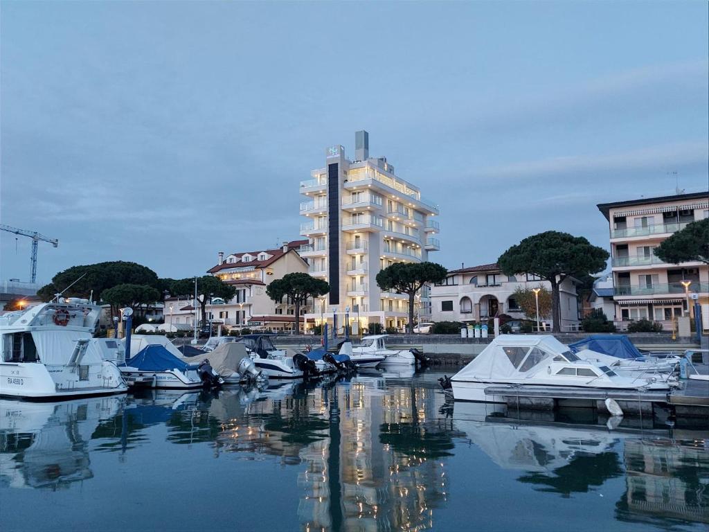 un groupe de bateaux amarrés dans un port avec un bâtiment dans l'établissement Hotel Mare, à Lignano Sabbiadoro
