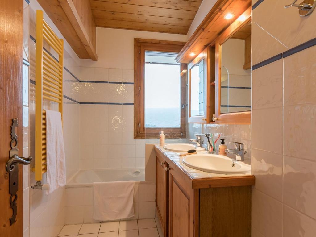 La salle de bains est pourvue d'un lavabo, d'une baignoire et d'une fenêtre. dans l'établissement Residence Les Hauts Bois - maeva Home, à Aime La Plagne