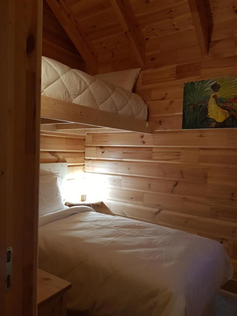 une chambre avec un lit dans une cabane en bois dans l'établissement Refuges des Hauts, à Bussang