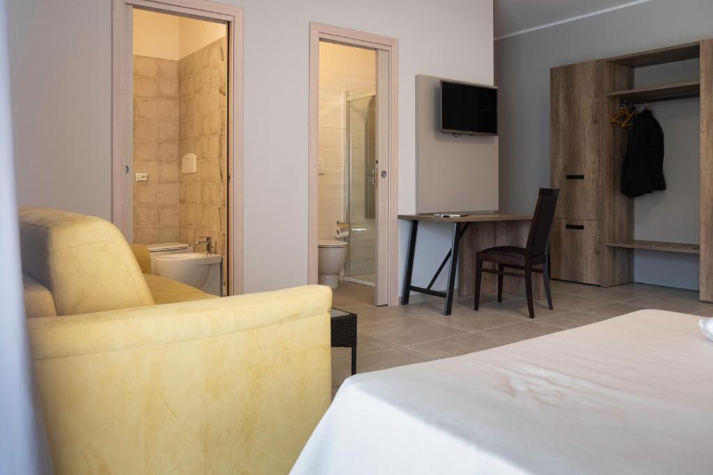 une chambre d'hôtel avec un canapé et une table avec une télévision dans l'établissement Hotel San Vincenzo Resort, à Policoro