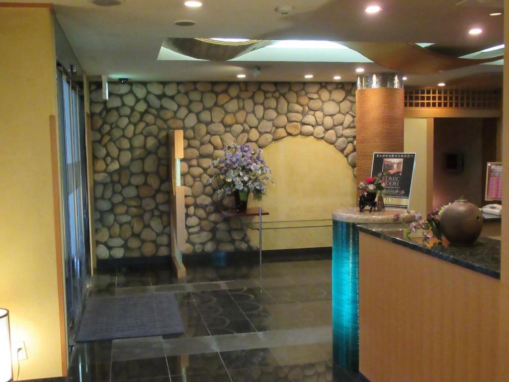 un hall d'entrée avec un mur de pierre avec des fleurs dessus dans l'établissement Hotel Shuyukan (Adult Only), à Izumi-Sano
