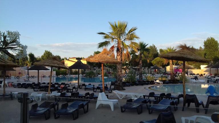 un complexe avec des chaises et des parasols et une piscine dans l'établissement SABLE DU MIDI chez gégé, à Valras-Plage