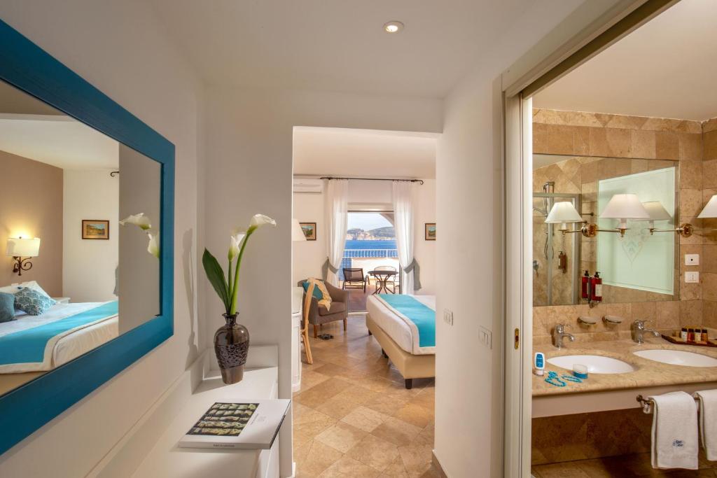 une chambre d'hôtel avec une salle de bains et une chambre dans l'établissement El Faro Hotel & Spa, à Porto Conte