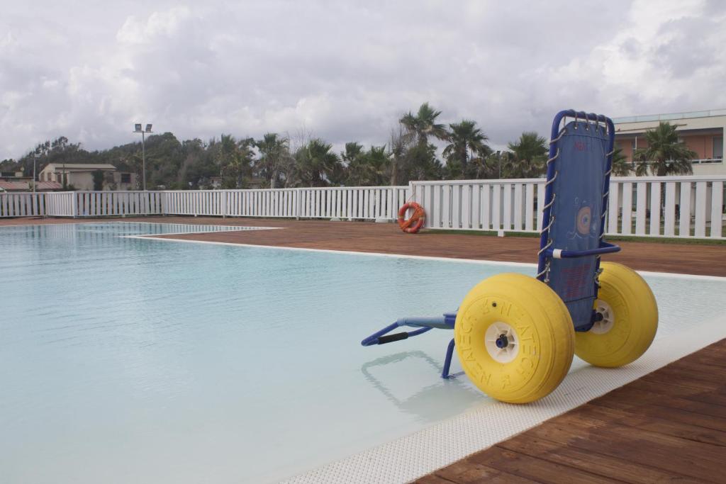 un tricycle bleu et jaune à côté d'une piscine dans l'établissement Sunrise Accessible Resort, à Battipaglia