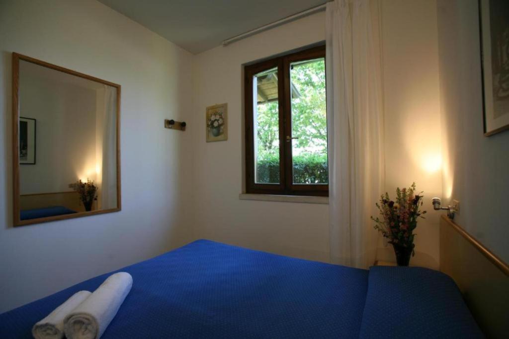 une chambre avec un lit bleu et une fenêtre dans l'établissement Villaggio Colombare, à Sirmione