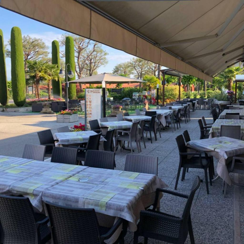 un patio extérieur avec tables, chaises et parasols dans l'établissement Villaggio Colombare, à Sirmione