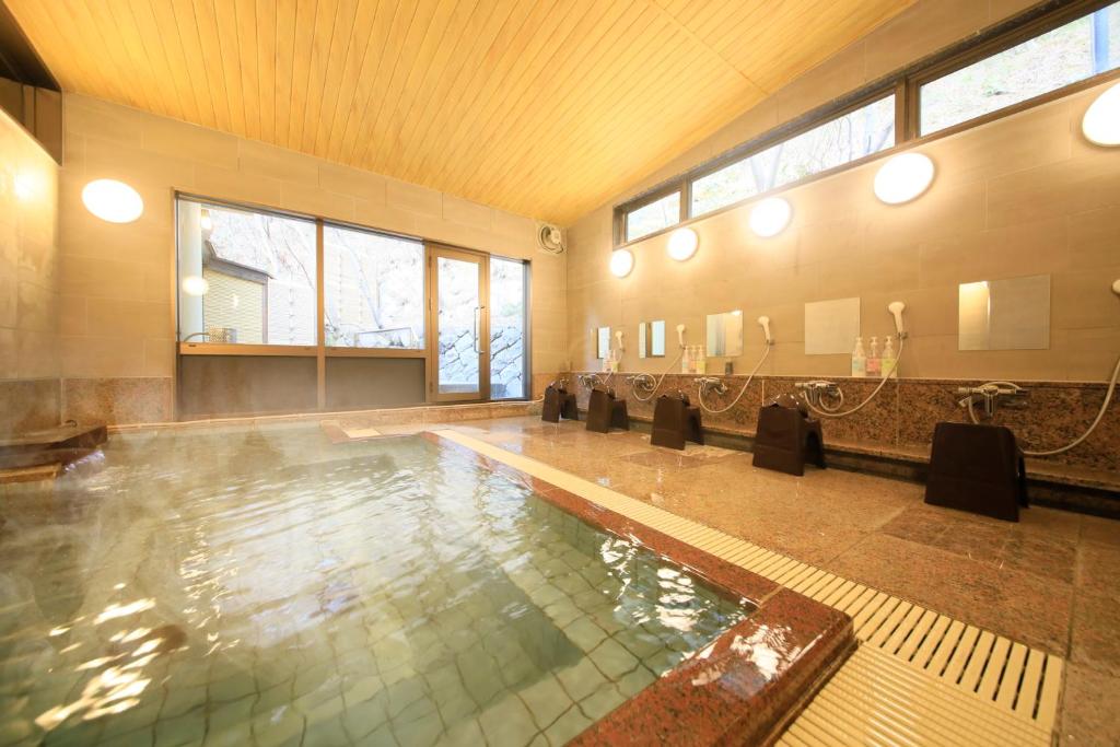 une grande piscine dans une salle de bain avec dans l'établissement Naruko Fuga, à Osaki