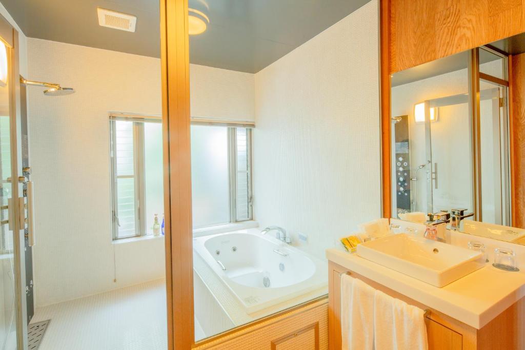 une salle de bain avec une baignoire, un lavabo et un miroir dans l'établissement Suisui Garden Ryokan (in the Art Hotel Kokura New Tagawa), à Kitakyūshū