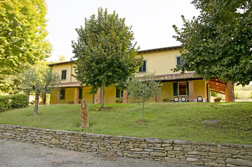 une maison jaune avec un mur en pierre et des arbres dans l'établissement Lucca Cycling Holidays Il Tiglio, à Lucques