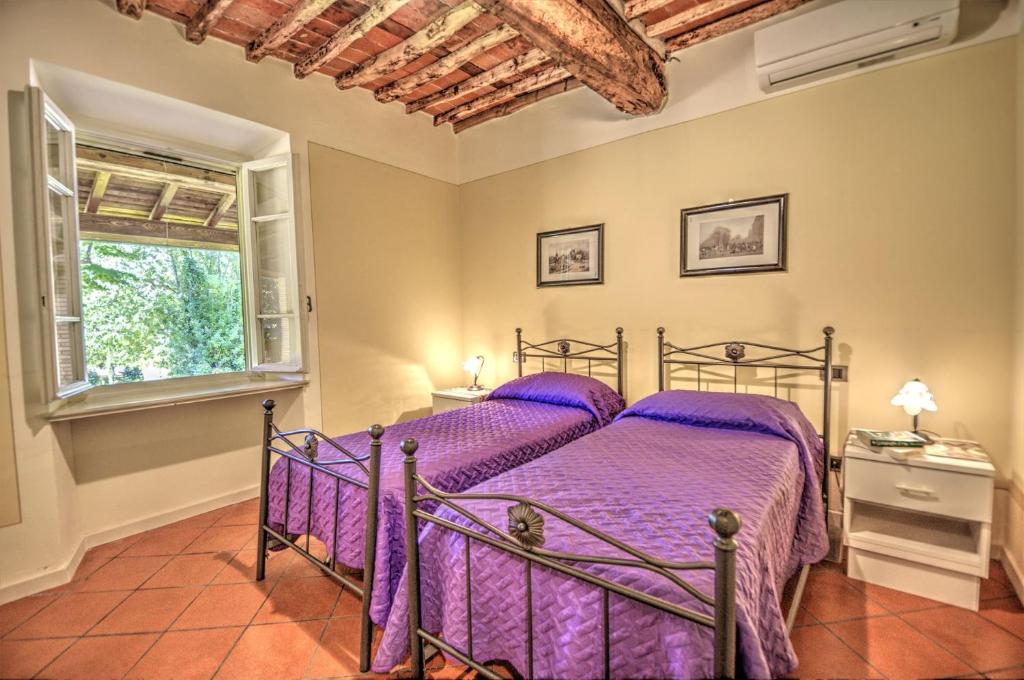 - une chambre avec un lit doté de draps violets et une fenêtre dans l'établissement Lucca Cycling Holidays Il Tiglio, à Lucques 21 autres photos