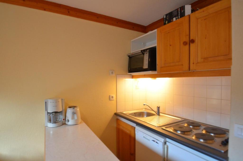 une petite cuisine avec un évier et un micro-ondes dans l'établissement Résidence Valmonts A, Les Ménuires, appartement 2 pièces, aux Menuires 8 autres photos