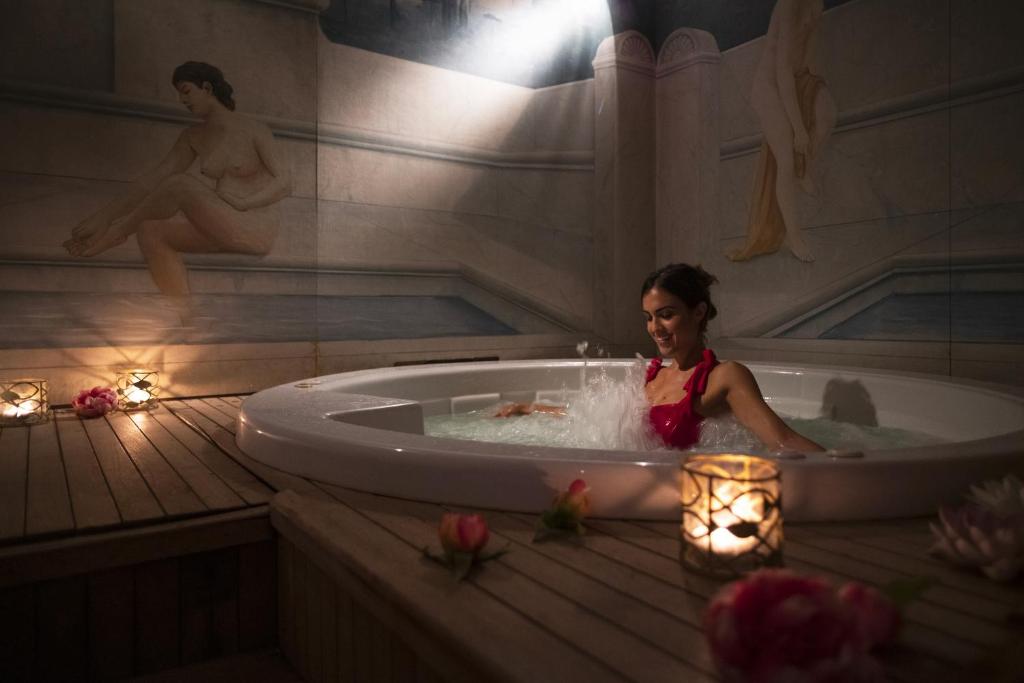 une femme assise dans une baignoire avec des lumières dans l'établissement Hotel Orizzonte, à Bellaria-Igea Marina