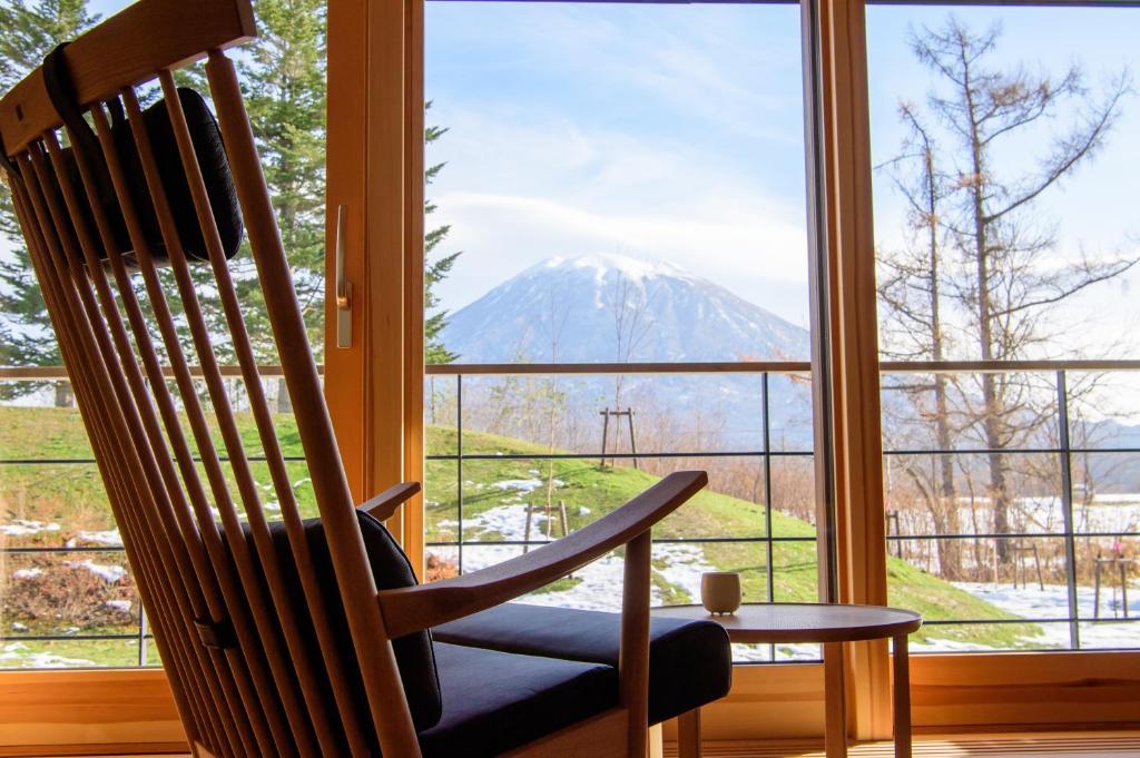- un fauteuil à bascule dans une chambre avec vue sur la montagne dans l'établissement NISEKO Inn of Youtei Raku Suisan, à Kutchan