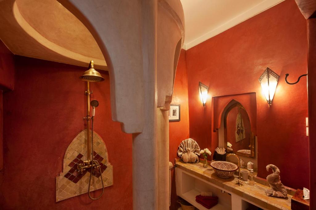 La salle de bains est pourvue de murs rouges et d'une croix sur le mur. dans l'établissement Riad Boussa, à Marrakech